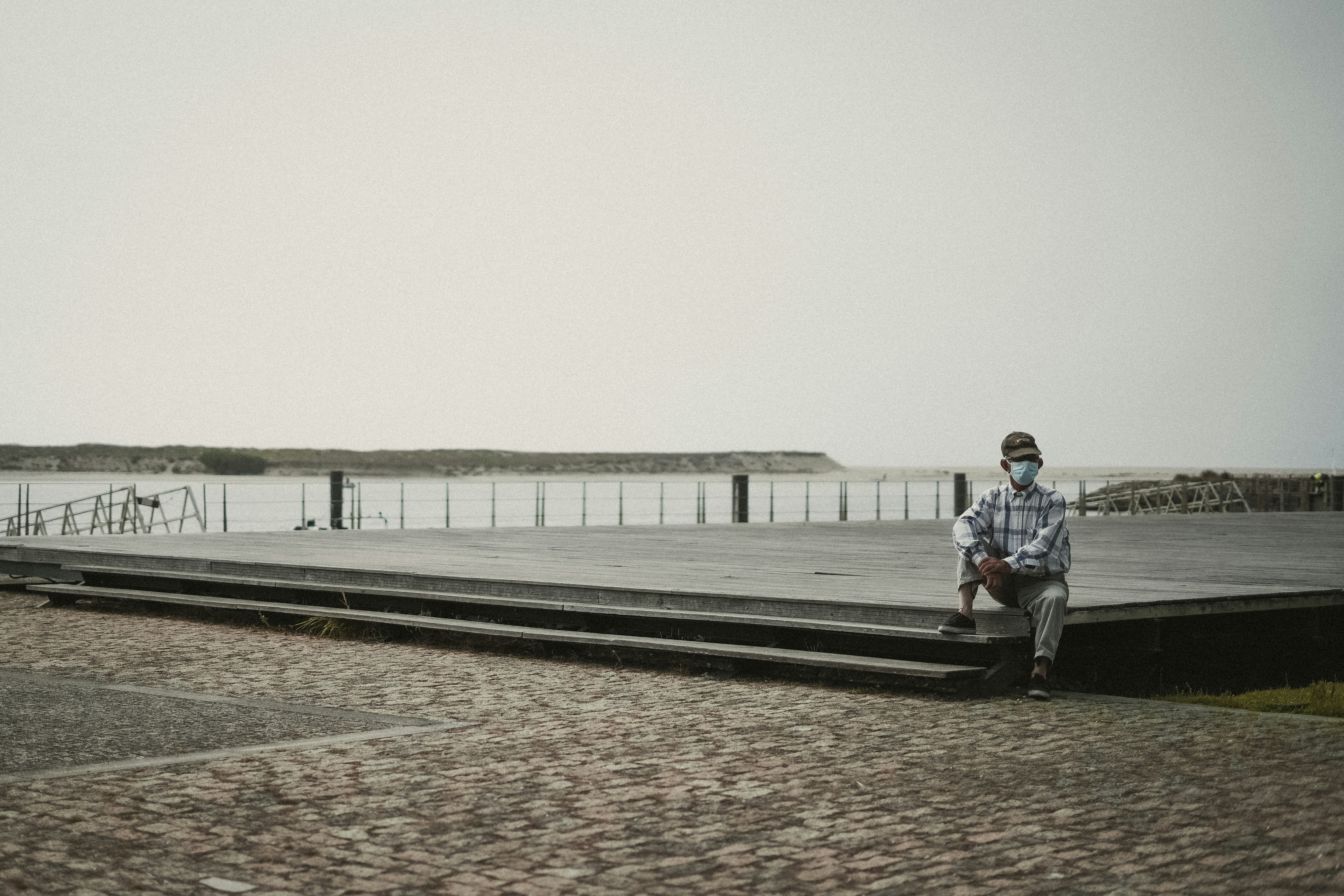 man in blue jacket and black pants sitting on bench